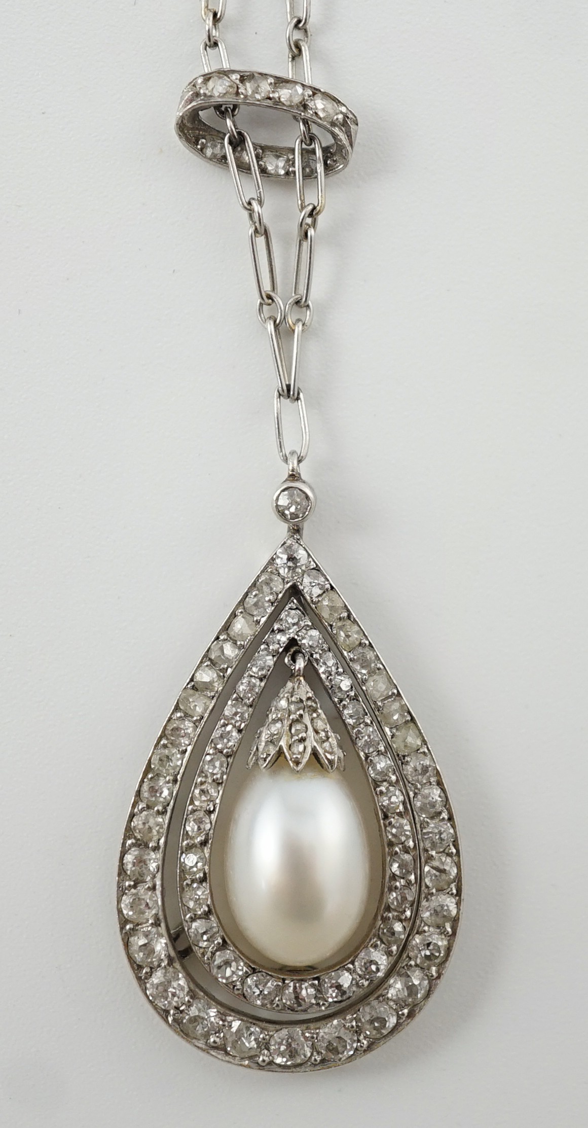 An early 20th century platinum, cultured? pearl and diamond cluster set pear shaped drop pendant necklace